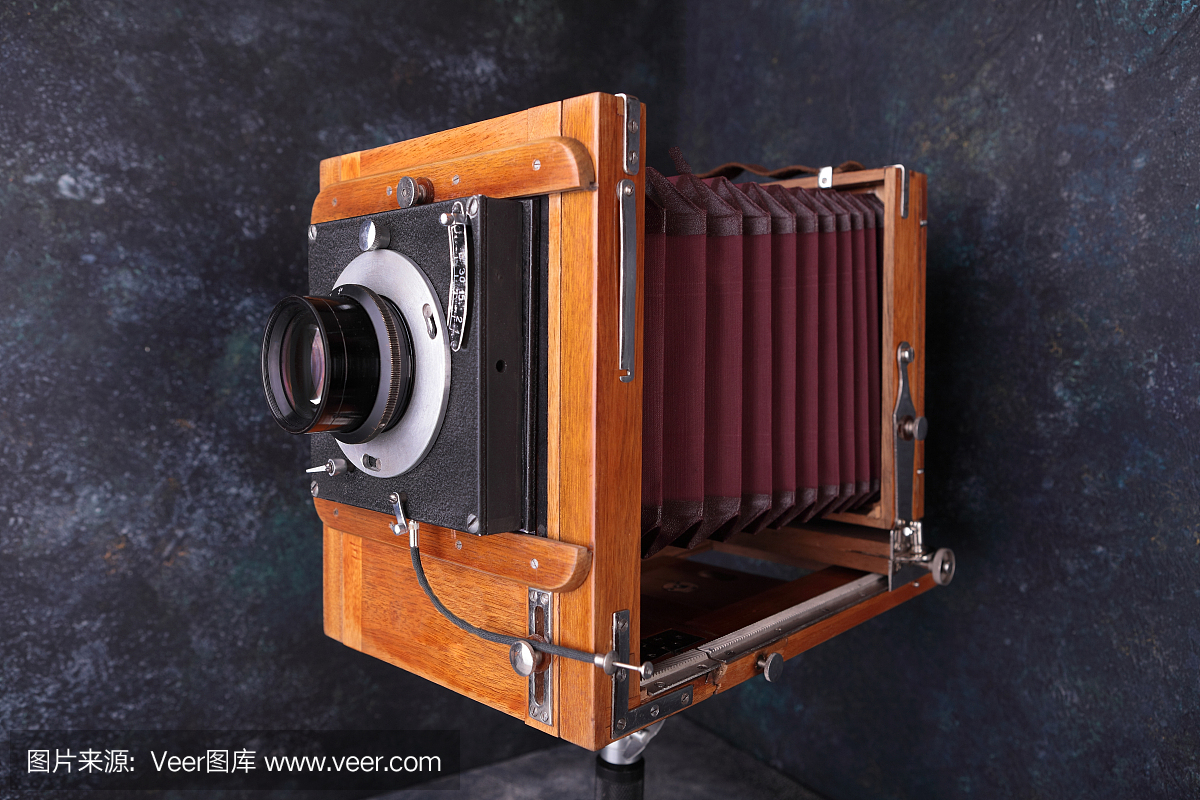 水泥背景上带快门的老式木制相机。使用底片的老式摄影棚相机。